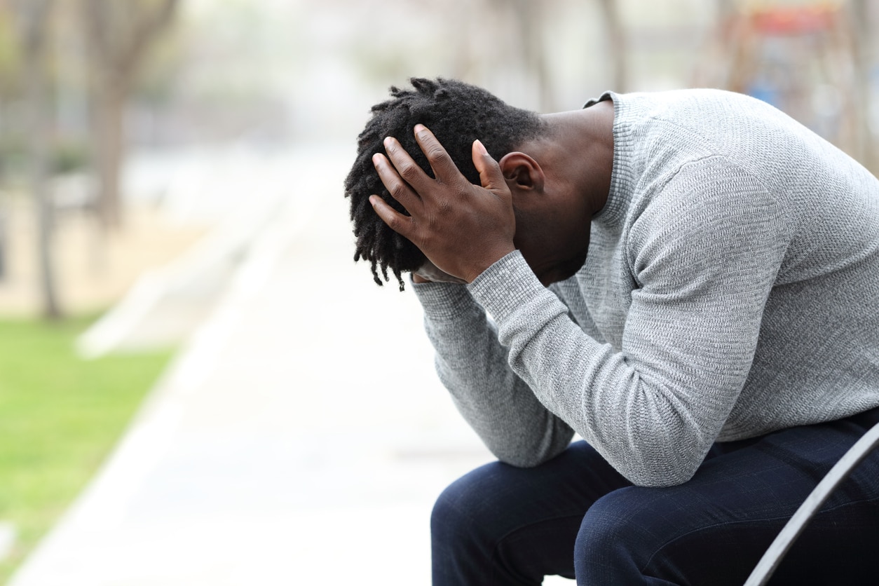 Sad depressed black man on a bench in a park - trauma and PTSD