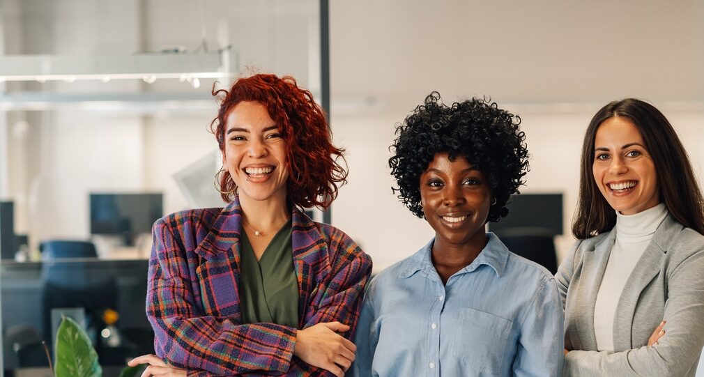 Female leaders standing together in the office and smiling at the camera