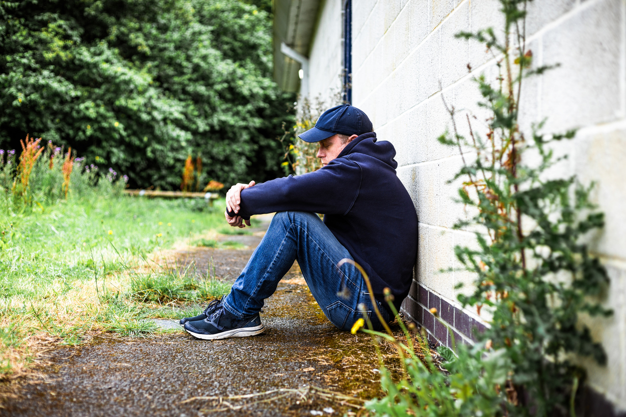 Depressed homeless man sitting outside abandoned building who could be thinking about suicide