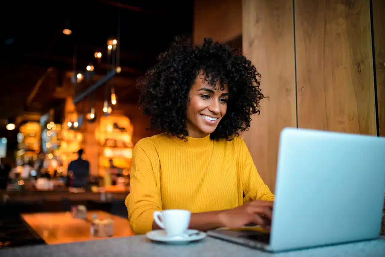 Young woman sitting in a coffee shop completing a micro-credential online