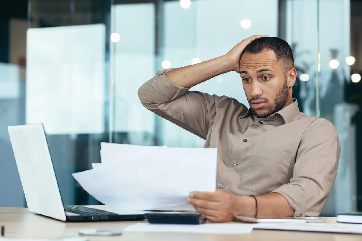 stressed out businessman who has taken on a lot of work in self-sabotaging behaviour making it difficult to meet deadlines