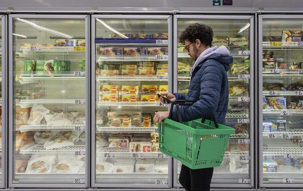 Consumer buying food at a grocery store looking at his shopping list