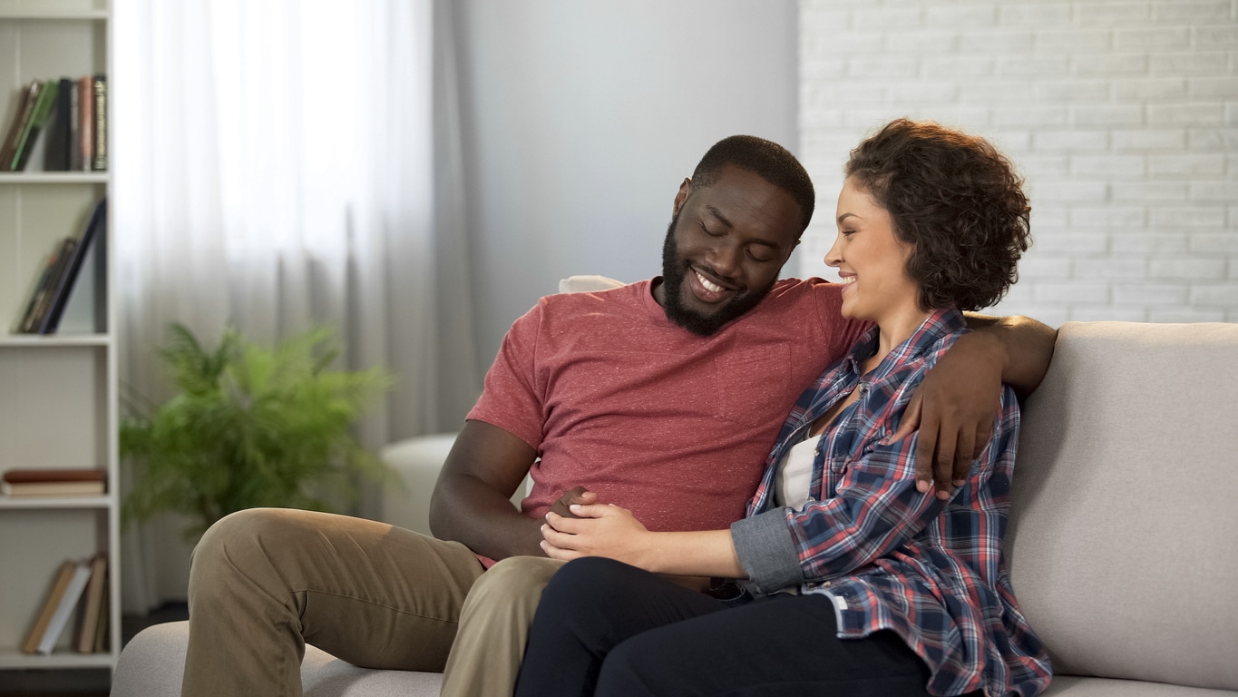 Couple sitting together and smiling while at home