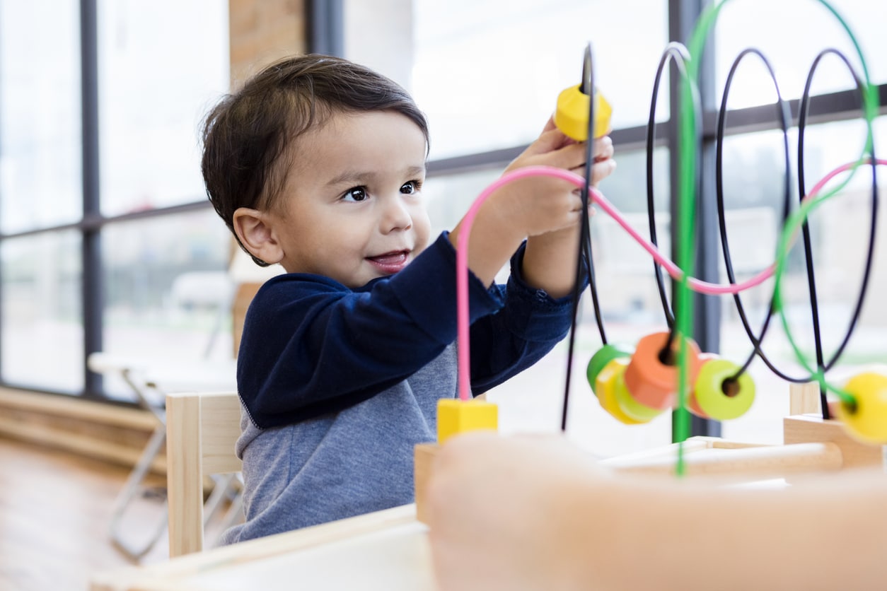 Boy plays while sitting in waiting room with unseen mother