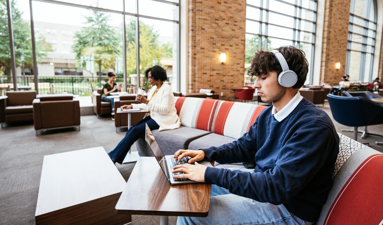 Young man sitting in a cafeteria working and learning online