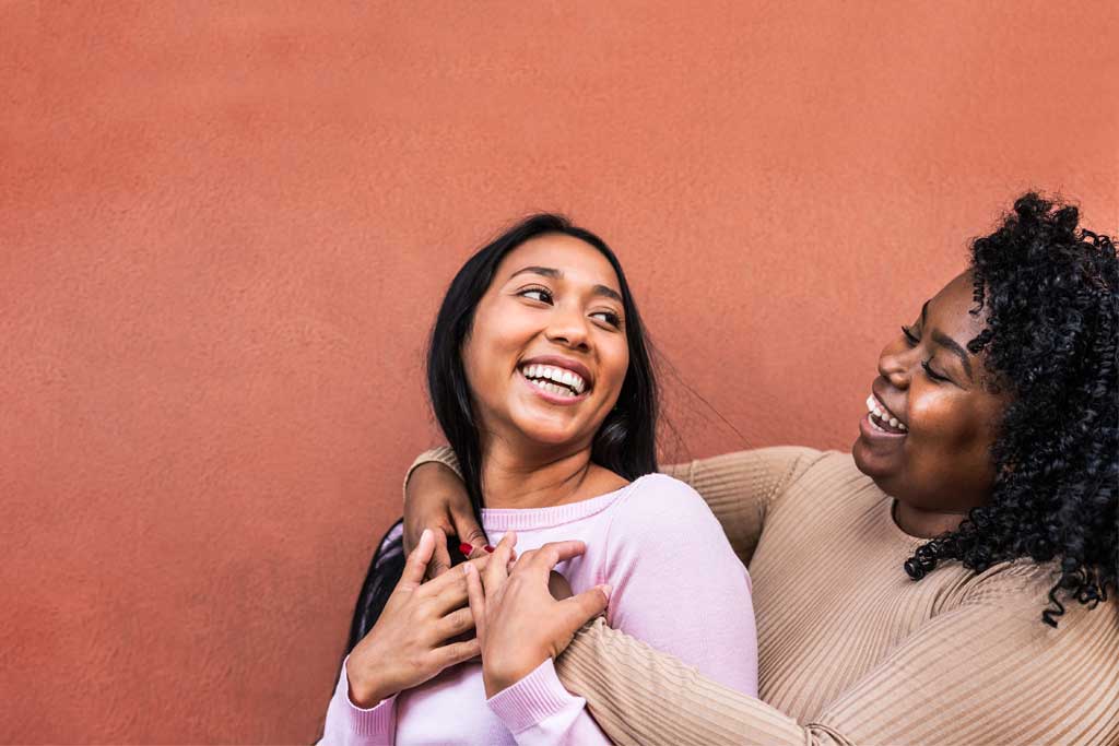 Portrait of happy Latin girls having fun embracing outdoor