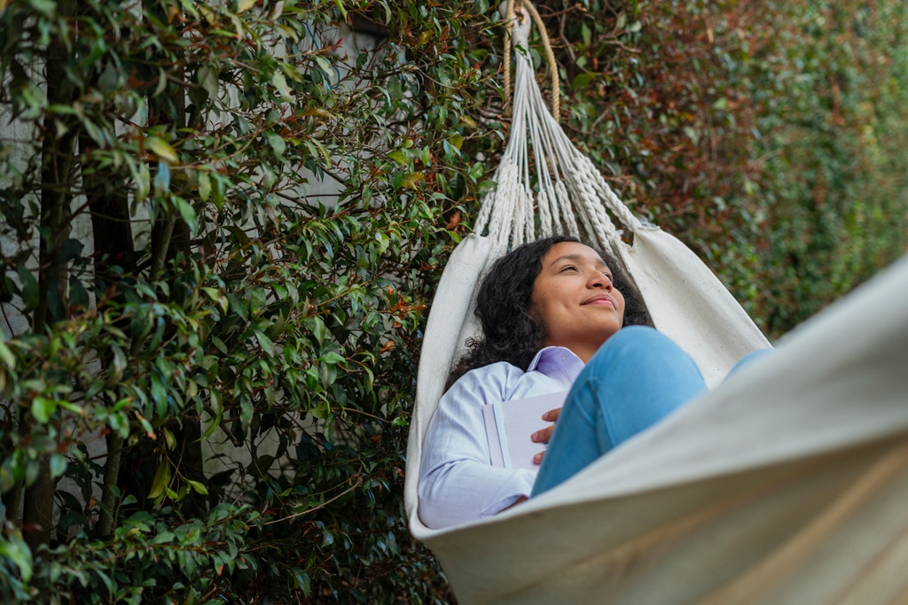 
		Latin woman enjoying the outdoors in the garden while on top of her hammock having a moment of reflection alone		