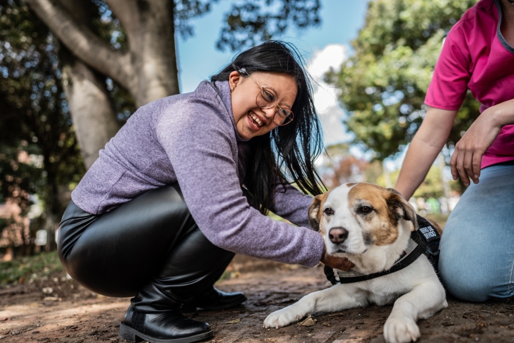 Young woman taking care of dog during therapy on a public park