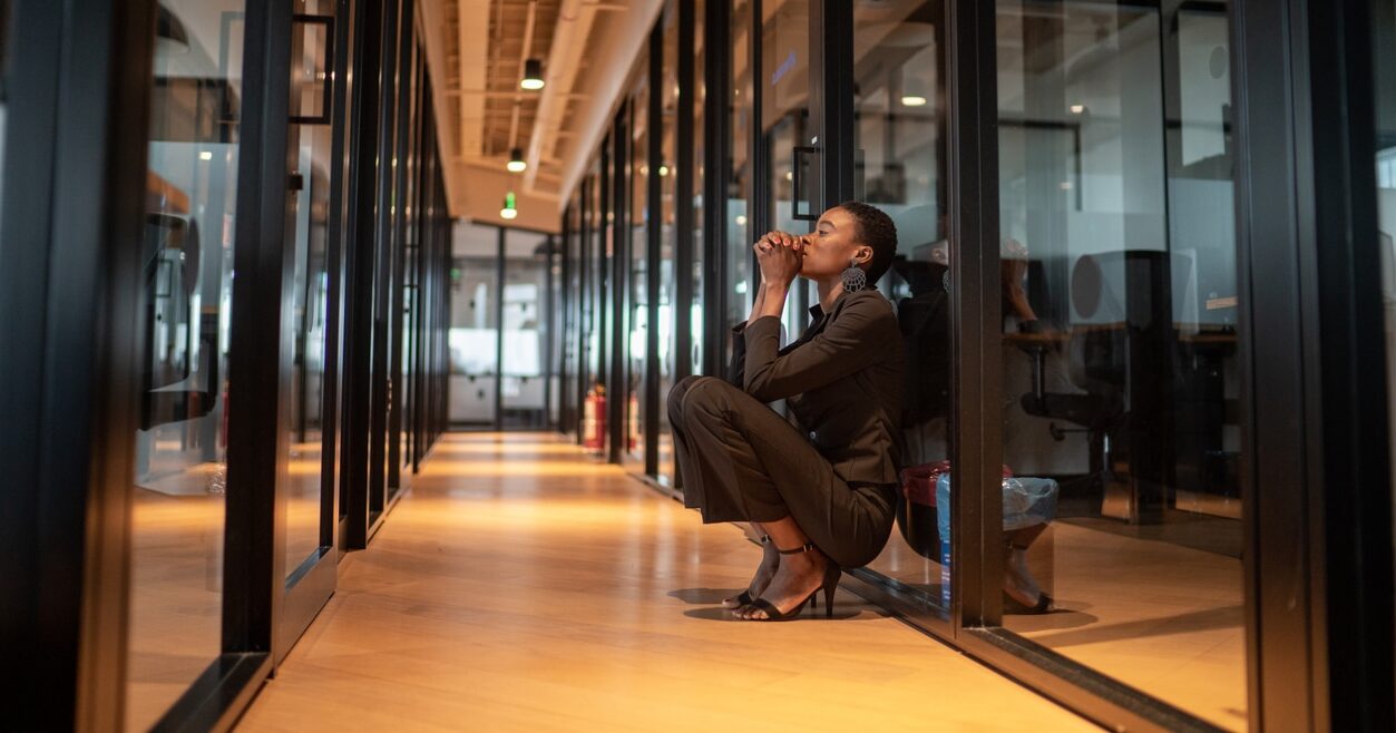 Business woman sitting in the hallway at work to manage anxiety